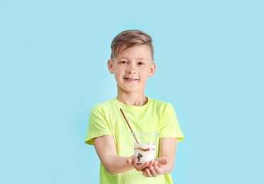 Little boy with yogurt on color background