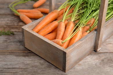 Basket with ripe carrots on wooden background