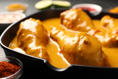 Photo of Tasty chicken curry and ingredients on table, closeup