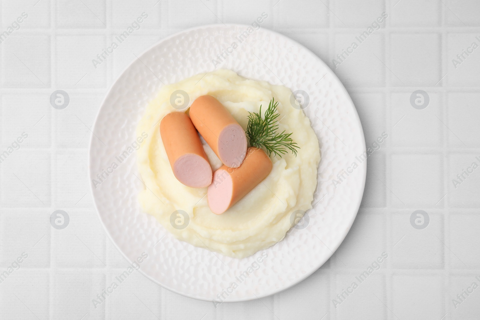 Photo of Delicious boiled sausages, mashed potato and dill on white tiled table, top view