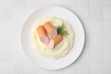 Photo of Delicious boiled sausages, mashed potato and dill on white tiled table, top view