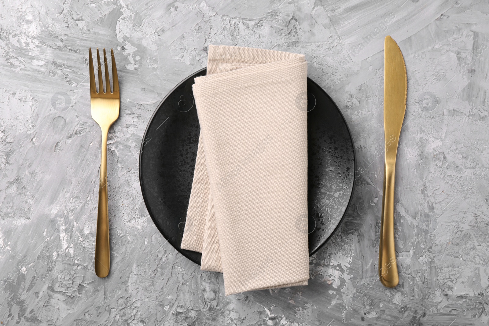 Photo of Elegant setting with golden cutlery on grey textured table, flat lay