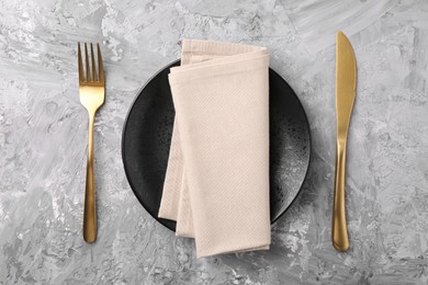 Elegant setting with golden cutlery on grey textured table, flat lay