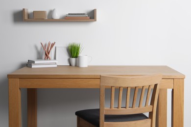 Photo of Comfortable workplace with wooden desk near white wall at home