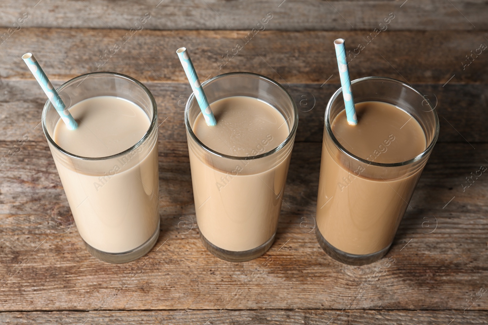 Photo of Glasses with protein shakes and straws on wooden background