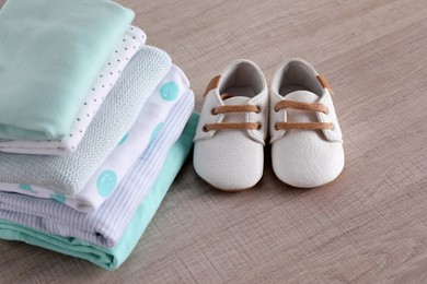 Stack of baby boy's clothes and shoes on wooden table