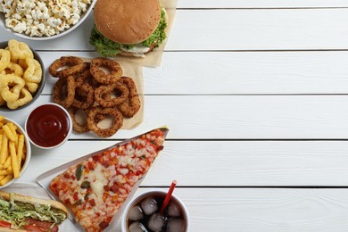 Pizza, onion rings and other fast food on white wooden table, flat lay with space for text