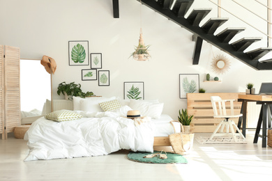 Elegant interior of bedroom with workplace under stairs