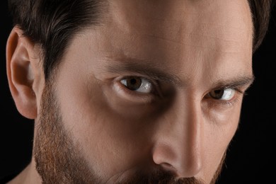 Photo of Evil eye. Man with scary eyes on black background, closeup