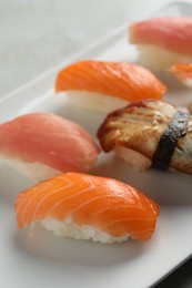 Photo of Plate with delicious nigiri sushi on grey table, closeup