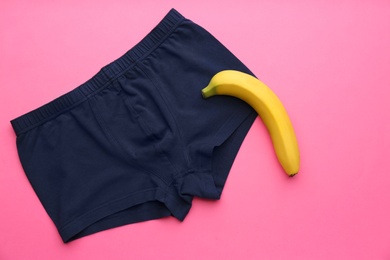 Photo of Men's underwear and banana on pink background, flat lay. Potency problem concept