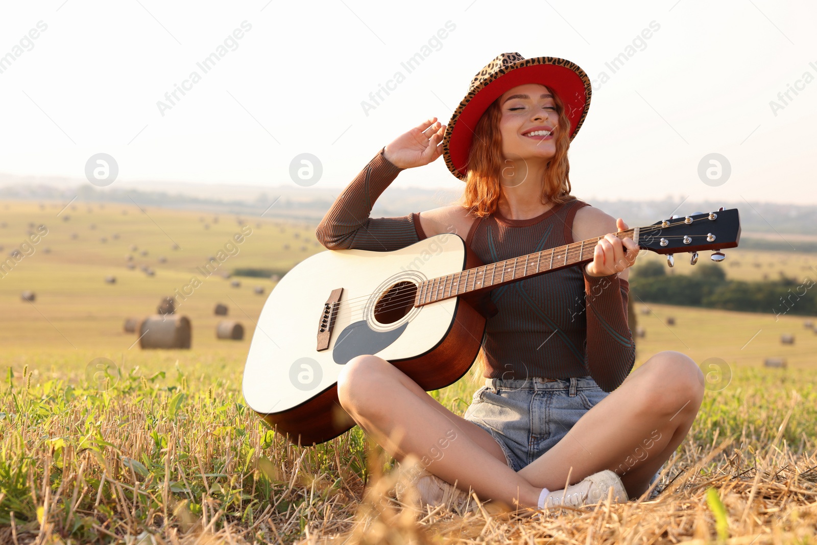 Photo of Beautiful happy hippie woman with guitar in field, space for text