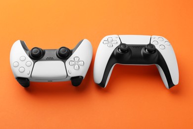 Two wireless game controllers on orange background