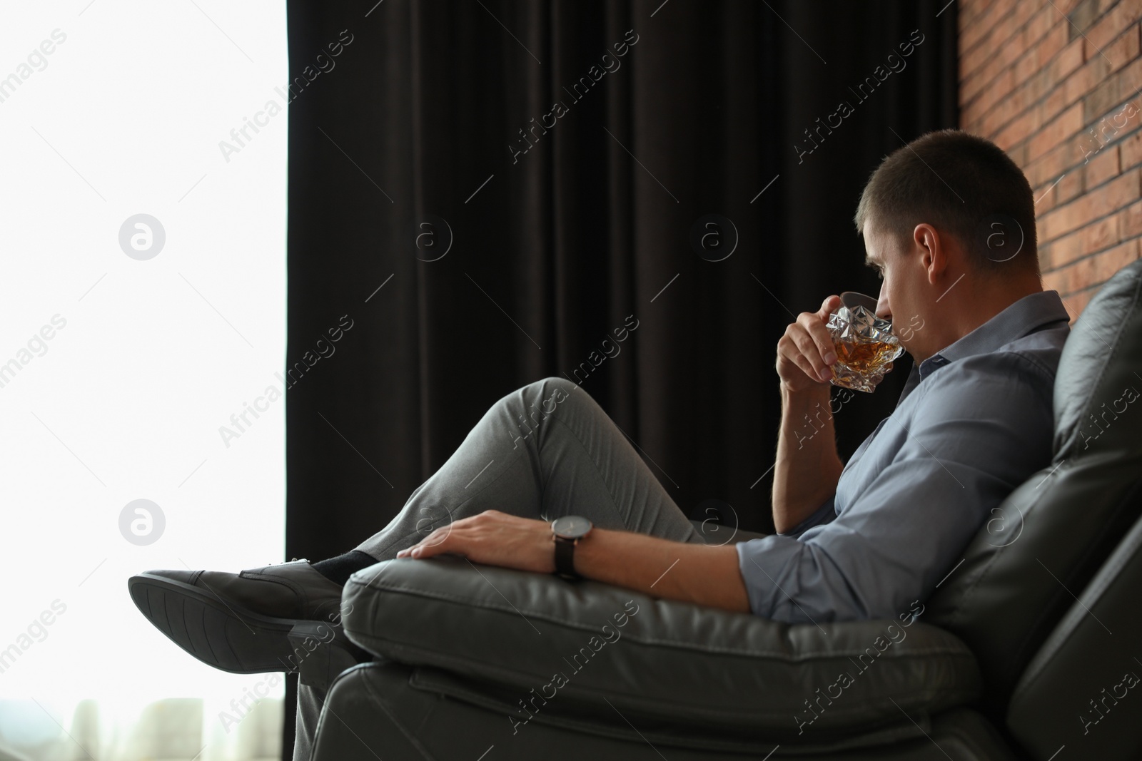 Photo of Young man with glass of whiskey indoors