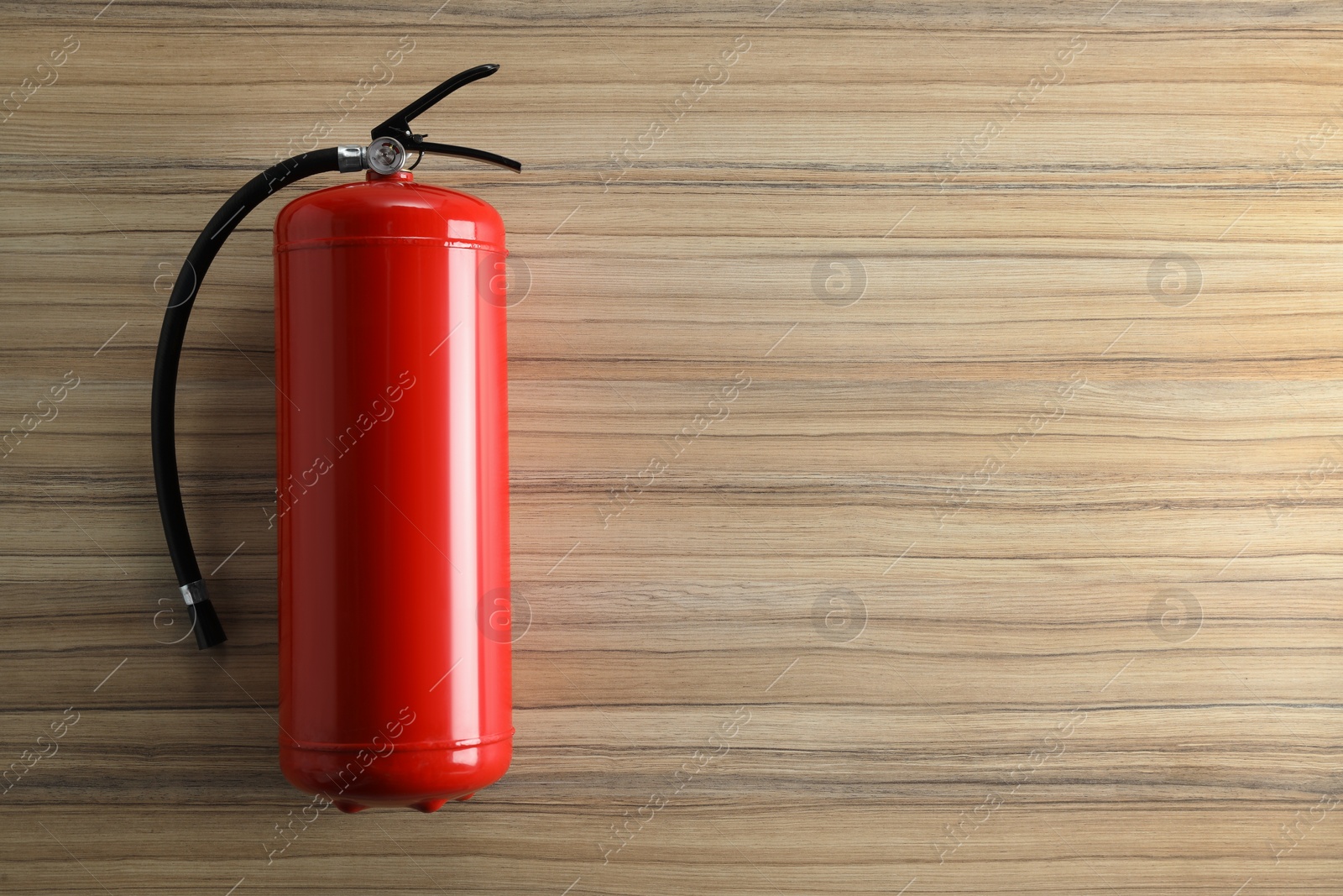 Photo of Fire extinguisher on wooden background, top view. Space for text