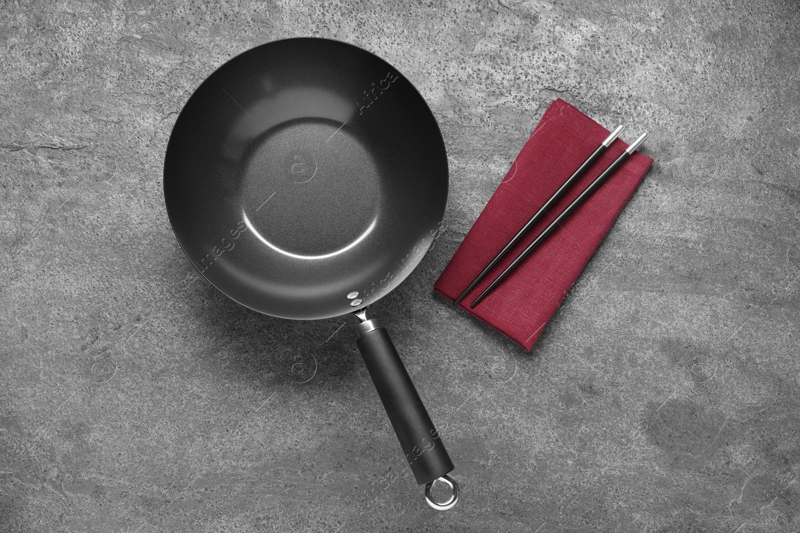 Photo of Empty iron wok and chopsticks on grey table, flat lay