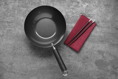 Photo of Empty iron wok and chopsticks on grey table, flat lay