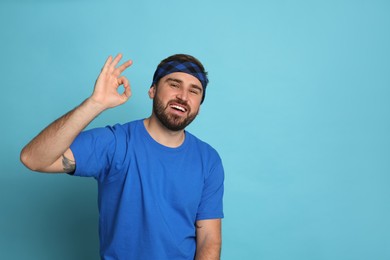 Fashionable young man wearing stylish bandana on light blue background, space for text