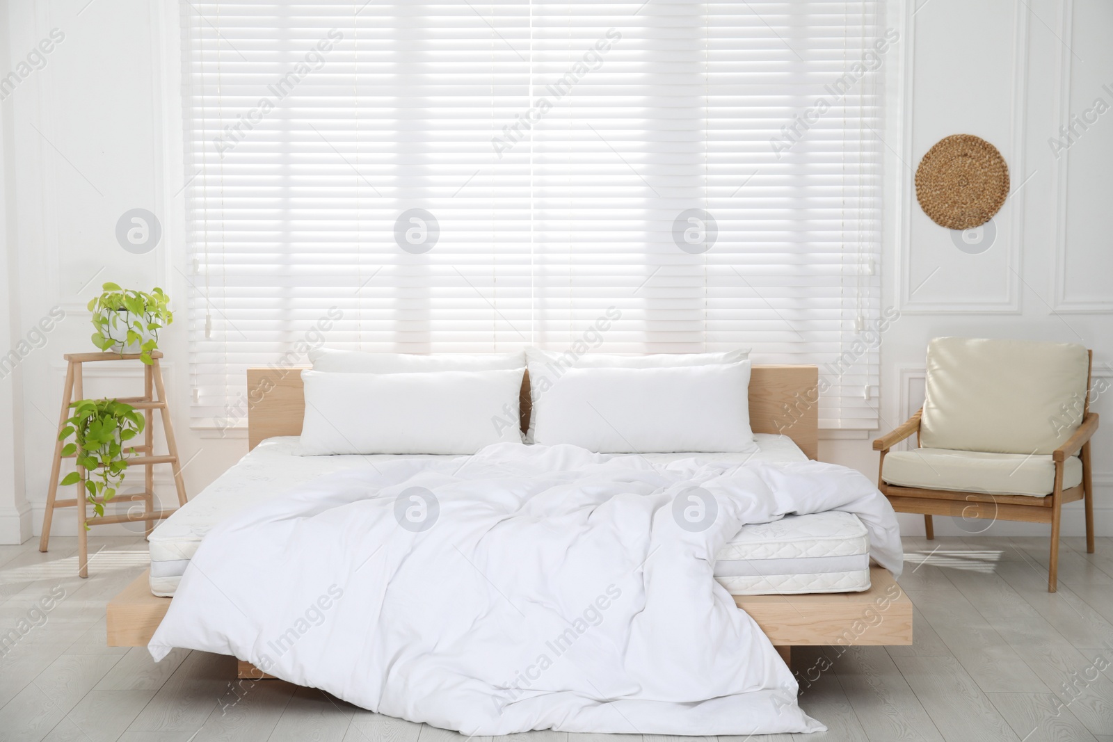 Photo of Wooden bed with soft white mattress, blanket and pillows in cozy room interior