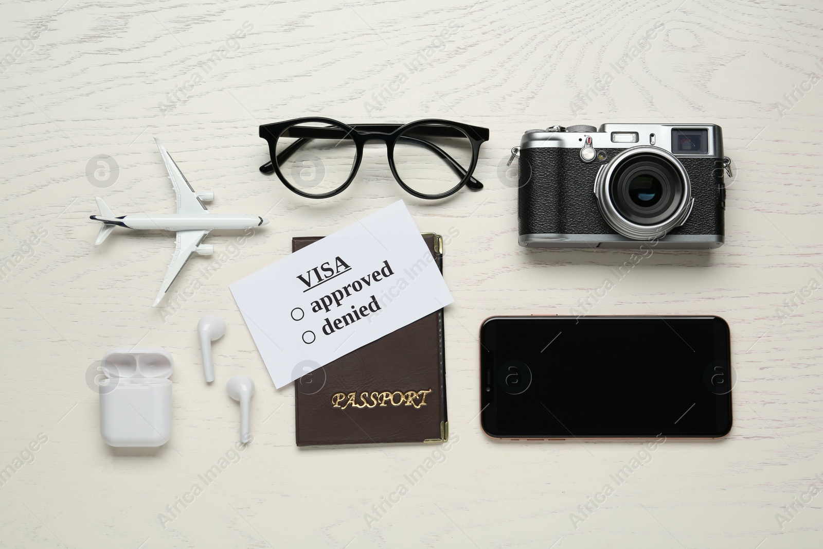 Photo of Flat lay composition with passport, toy plane and camera on white wooden table. Visa receiving