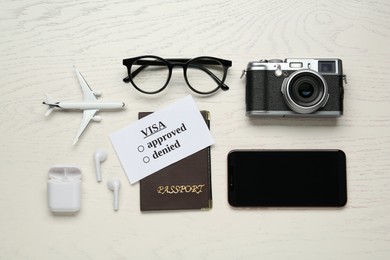 Photo of Flat lay composition with passport, toy plane and camera on white wooden table. Visa receiving