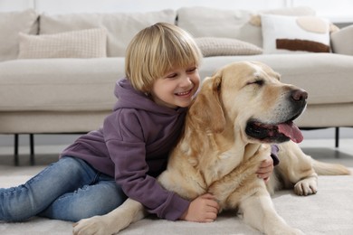 Cute little child with Golden Retriever on floor at home. Adorable pet