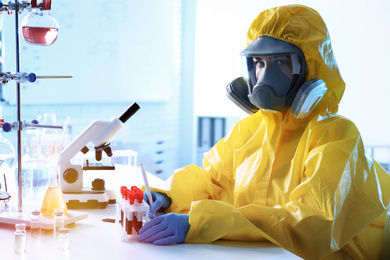 Scientist in chemical protective suit working with blood samples at laboratory. Virus research