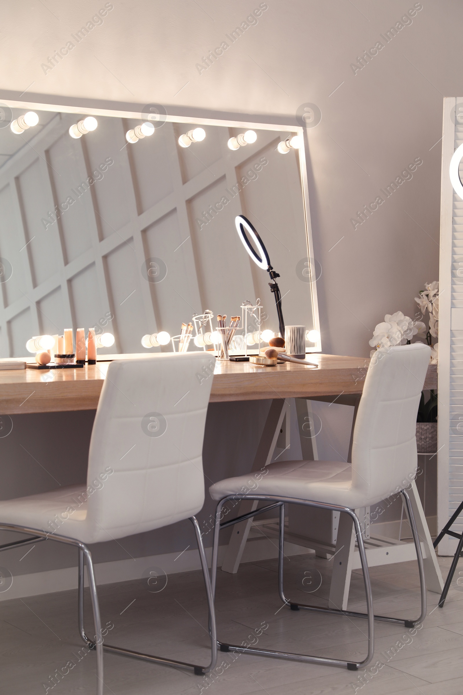 Photo of Modern mirror with light bulbs on dressing table in makeup room