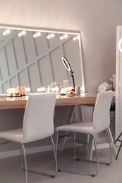 Photo of Modern mirror with light bulbs on dressing table in makeup room