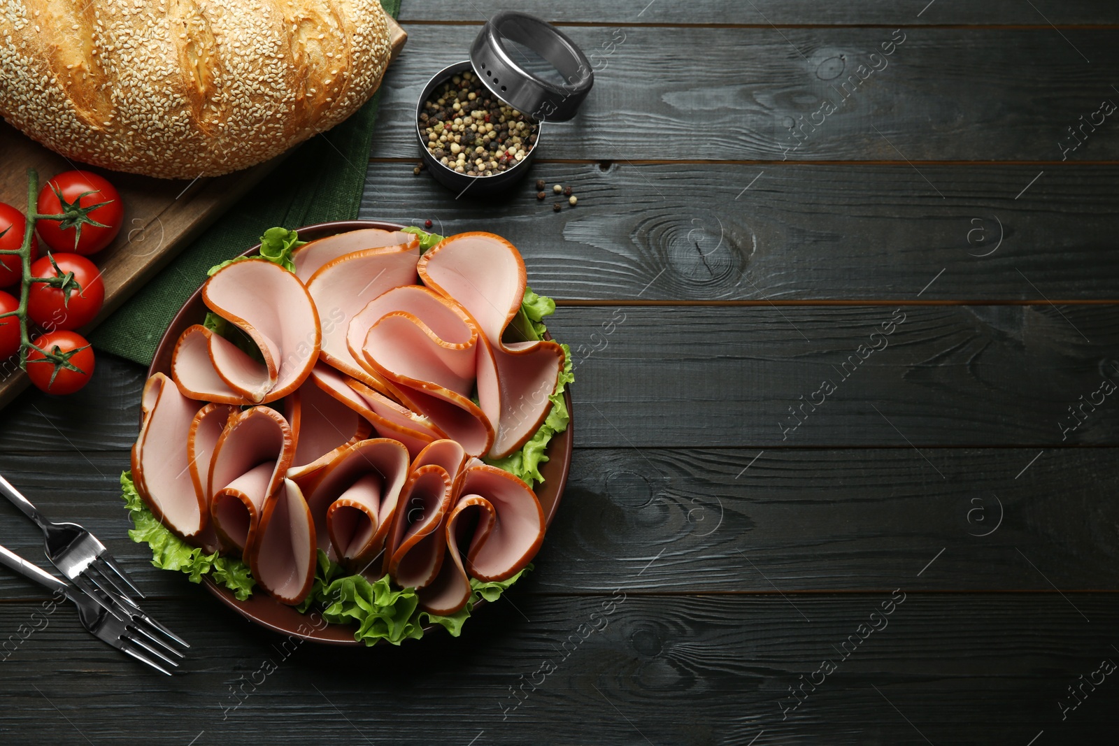 Photo of Slices of delicious boiled sausage and other products on dark wooden table, flat lay. Space for text