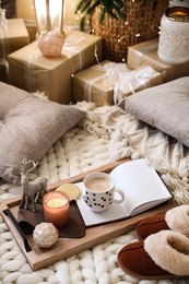 Photo of Wooden tray with cocoa, candle and notebook in room decorated for Christmas