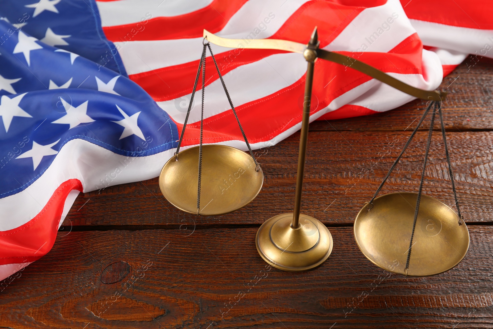 Photo of Scales of justice and American flag on wooden table