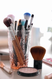 Holder with makeup brushes on table