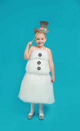 Image of Cute little girl dressed as snowman on light blue background. Christmas suit