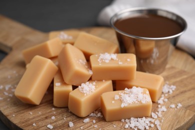 Photo of Yummy caramel candies and sea salt on wooden table, closeup