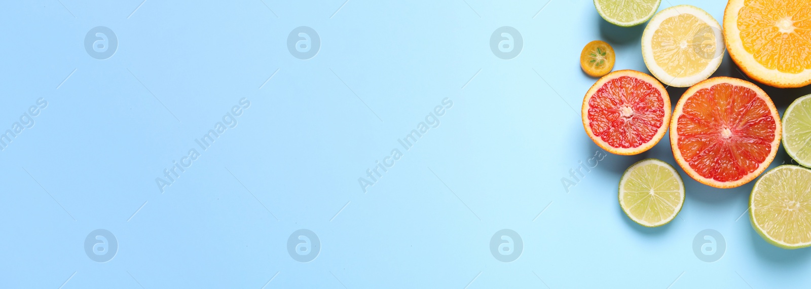 Photo of Fresh juicy citrus fruits on light blue background, flat lay. Space for text