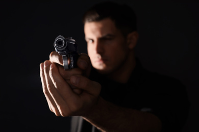 Professional killer on black background, focus on gun