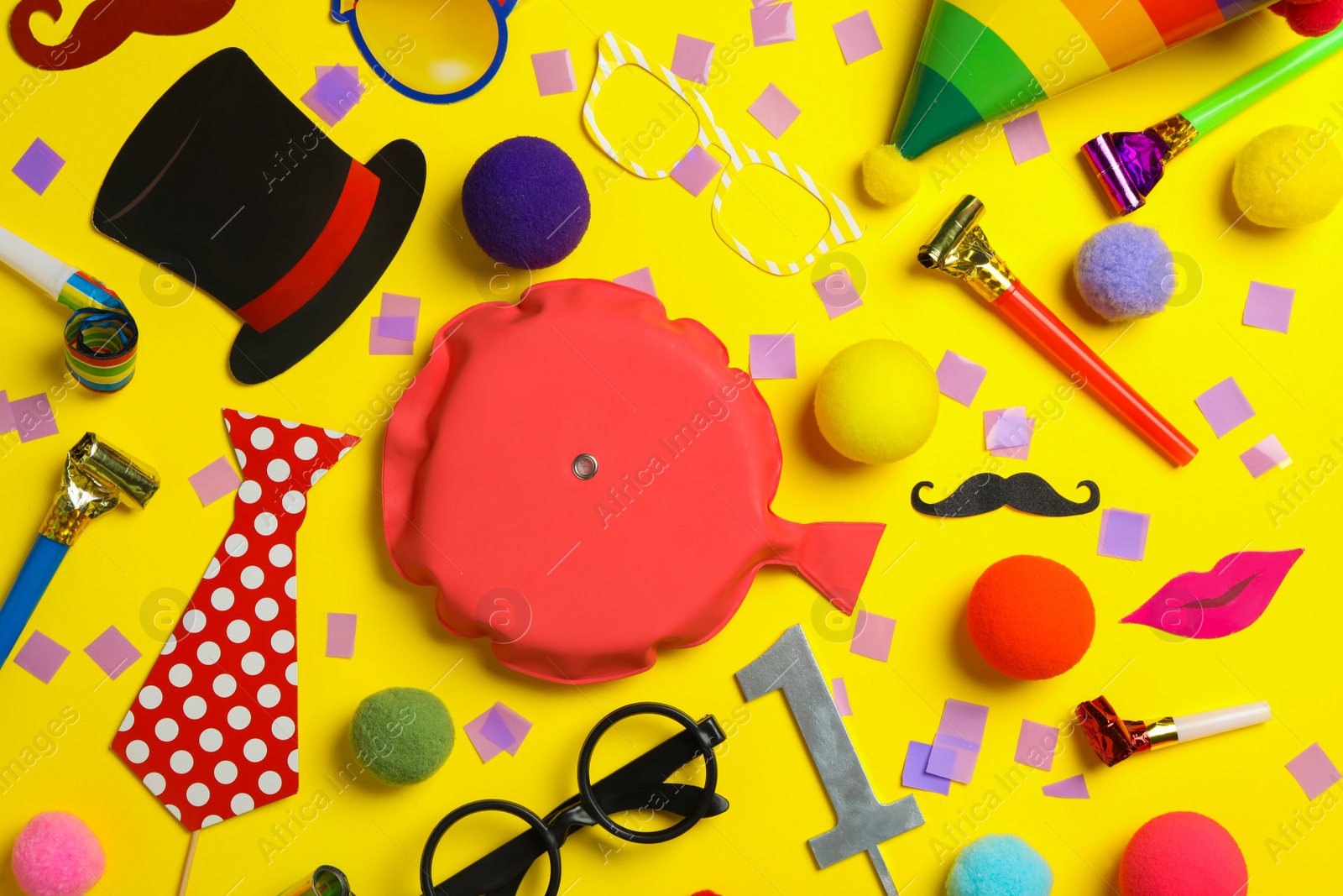 Photo of Different clown's accessories on yellow background, flat lay