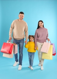 Photo of Happy family with paper bags on light blue background. Christmas shopping