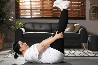 Overweight mature woman doing abs exercise at home