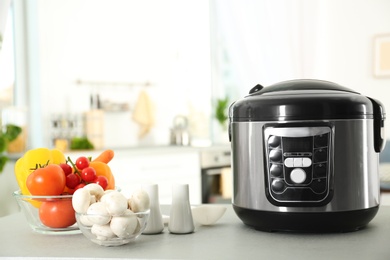 Modern multi cooker and products on table in kitchen