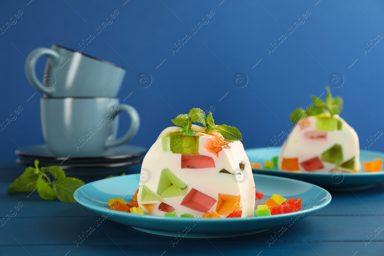 Photo of Delicious broken glass jelly dessert on blue wooden table