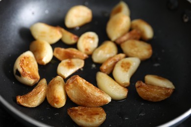 Photo of Frying pan with fried garlic cloves, closeup