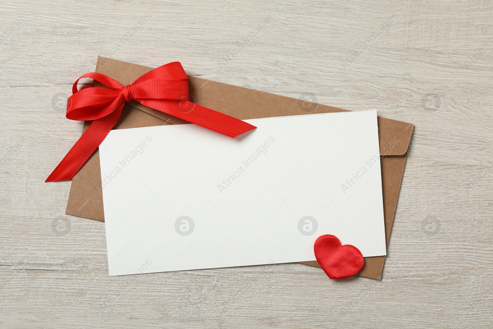 Photo of Blank card, envelope and decorative heart on wooden background, flat lay with space for text. Valentine's Day celebration