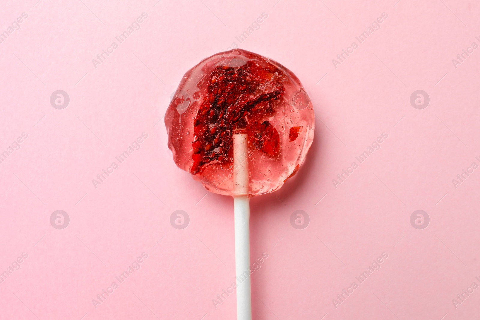 Photo of Sweet colorful lollipop with berries on pink background, top view