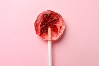 Photo of Sweet colorful lollipop with berries on pink background, top view