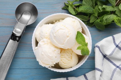 Photo of Delicious vanilla ice cream with mint and scoop on light blue wooden table, flat lay