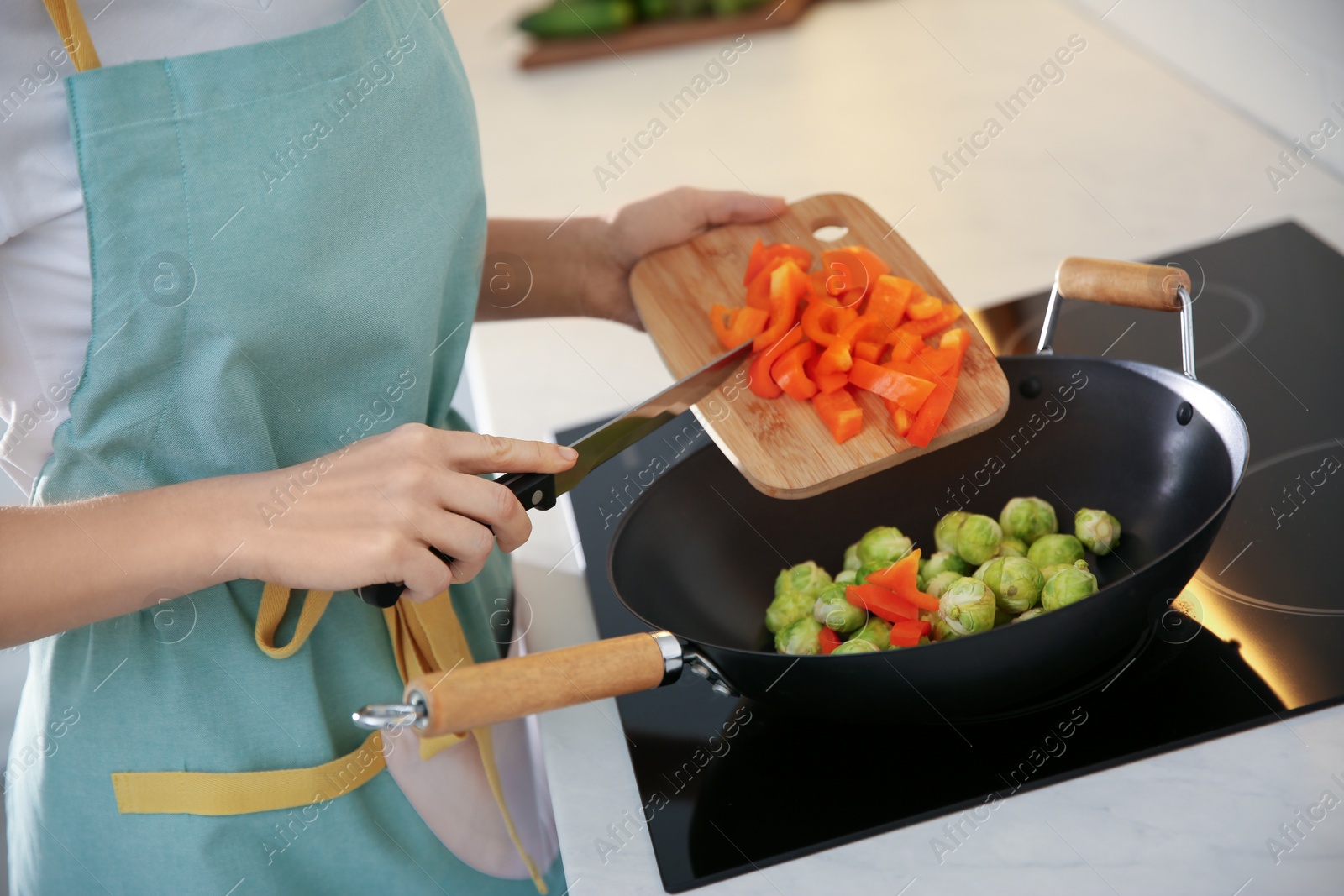 Photo of Young woman cooking on stove in kitchen, closeup