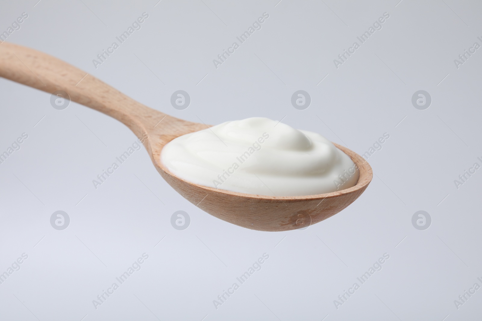 Photo of Delicious natural yogurt in spoon on light background