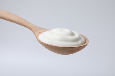 Delicious natural yogurt in spoon on light background